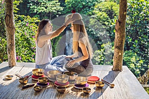 Nepal Buddha copper singing bowl at spa salon. Young beautiful woman doing massage therapy singing bowls in the Spa