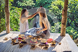 Nepal Buddha copper singing bowl at spa salon. Young beautiful woman doing massage therapy singing bowls in the Spa