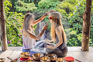 Nepal Buddha copper singing bowl at spa salon. Young beautiful woman doing massage therapy singing bowls in the Spa