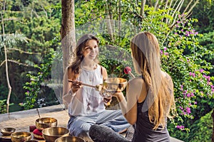 Nepal Buddha copper singing bowl at spa salon. Young beautiful woman doing massage therapy singing bowls in the Spa