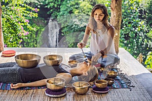 Nepal Buddha copper singing bowl at spa salon. Young beautiful woman doing massage therapy singing bowls in the Spa