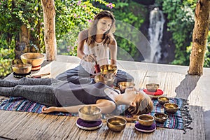 Nepal Buddha copper singing bowl at spa salon. Young beautiful woman doing massage therapy singing bowls in the Spa