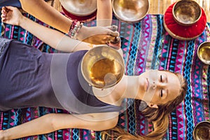 Nepal Buddha copper singing bowl at spa salon. Young beautiful woman doing massage therapy singing bowls in the Spa