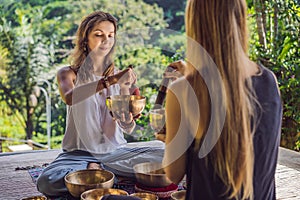 Nepal Buddha copper singing bowl at spa salon. Young beautiful woman doing massage therapy singing bowls in the Spa