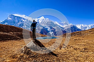 Nepal - Man standing on a rock in the nearby of the Ice Lake, Annpurna Circuit Trek in Himalayas. photo