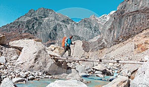 Nepalese Guide crossing Mountain River throw wooden Bridge