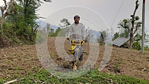 A Nepali man using mini tiller on their fields