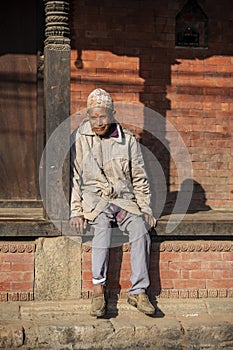 A Nepali senior gentleman sits on step , Nepal