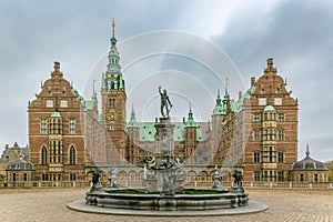 Neptune Fountain in front of Frederiksborg Castle on a cloudy day. Hillerod, Denmark.