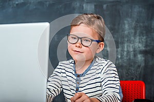 Nerd child in glasses using a laptop computer. Kid has online lesson. Back to school