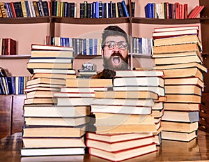 Nerd concept. Teacher or student with beard wears eyeglasses, sits at table with books, defocused. Man, nerd on
