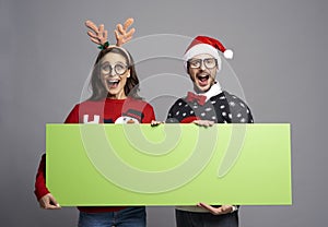 Nerd couple holding greenscreen Christmas banner