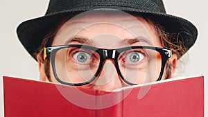 Nerd guy in glasses hiding behind book. Book lover. Excited man in glasses has great idea. Education concept. Face expression.