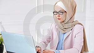 Nerd muslim woman in hijab is working on a graduation bachelor project typing on laptop