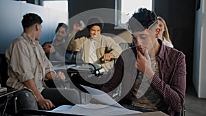 Nerd student sits in classroom at desk alone reads summary suffers from cruel aggressive attitude from classmates young