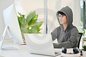 Nerd young Asian male website developer or programmer focusing on his task on computer