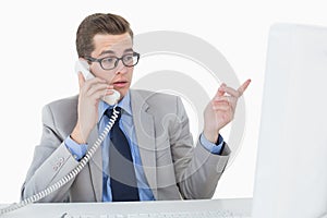 Nerdy businessman working on computer talking on phone