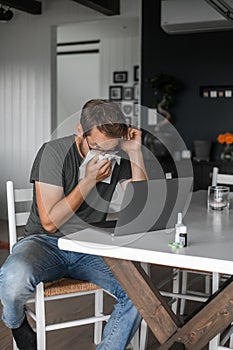 Nerdy man with glasses freelance working from home during the covid pandemic or flu