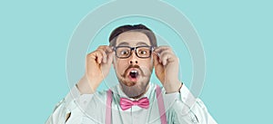 Nerdy man in glasses, shirt and bow tie looking at camera with funny surprised face expression