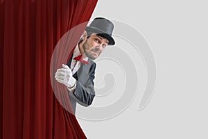 Nervous actor or illusionist is hiding behind red curtain in theater