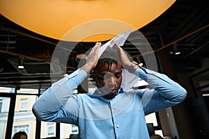 Nervous African American boss holding head with hands with documents