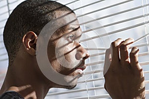 Nervous African American man at window, horizontal