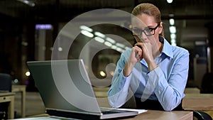 Nervous business woman looking at laptop, afraid of work failure and bad news