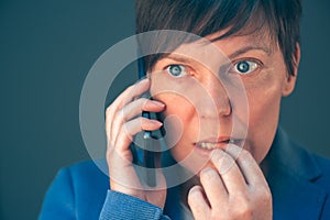 Nervous businesswoman bites fingernails during telephone convers