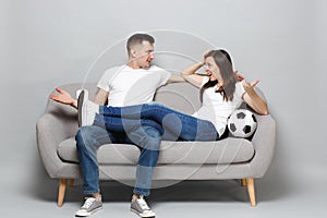 Nervous couple woman man football fans cheer up support favorite team with soccer ball spreading hands looking at each