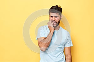 Nervous embarassed bearded man bites nails, looks worried before exams