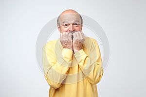 Nervous embarassed man bites nails, looks worried before visiting doctor or dentist.