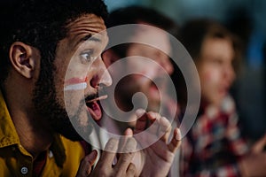 Nervous football fans friends watching German national team in live soccer match on TV at home