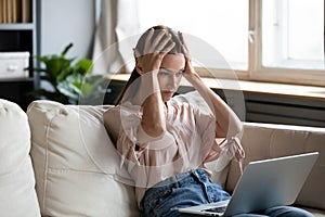 Nervous frustrated young woman looking at computer screen.