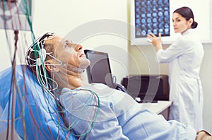 Nervous gentleman getting brain analyzed by electroencephalography machine photo
