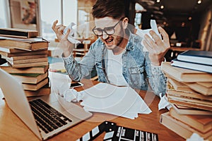 Nervous Guy Sitting at Table With Stacks of Books