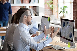 Nervous male employee gesturing angry about computer problem