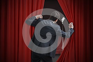 Nervous man is afraid of public speech and is hiding behind curtain photo