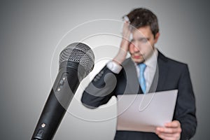 Nervous man is afraid of public speech and sweating. Microphone in front