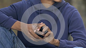 Nervous mixed-race teen male reading cellphone bad-news message, troubles