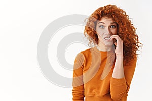 Nervous silly redhead cute woman with curly hair biting fingernails awkward situation, feeling guilt making small