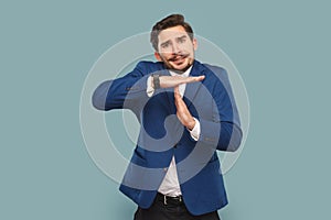 Nervous stressed man with mustache standing showing time limit gesture, warning about deadline.