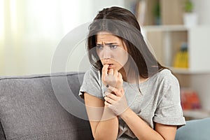 Nervous teen biting nails alone at home