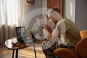 Nervous veteran talking loudly to psychiatrist during videoconferencing photo