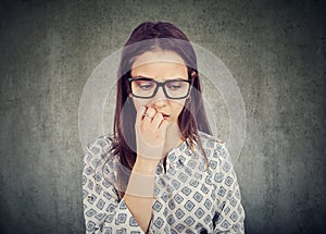 Nervous woman biting nails and looking down