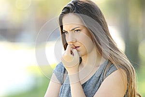 Nervous woman biting nails outdoors