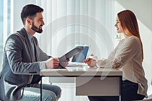 Nervous woman looking at manager reading her resume during a job interview at office