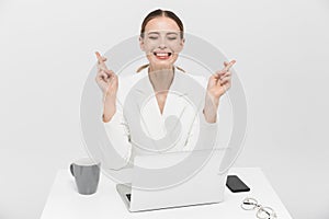 Nervous woman posing isolated over white wall background using laptop computer make hopeful gesture