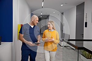 Nervous woman talking to doctor while walking through hospital corridor