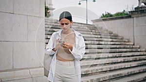 Nervous woman typing cellphone fast outdoors. Worried student girl feeling lost