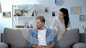 Nervous woman criticizing lazy husband sitting on sofa, family conflict, problem photo